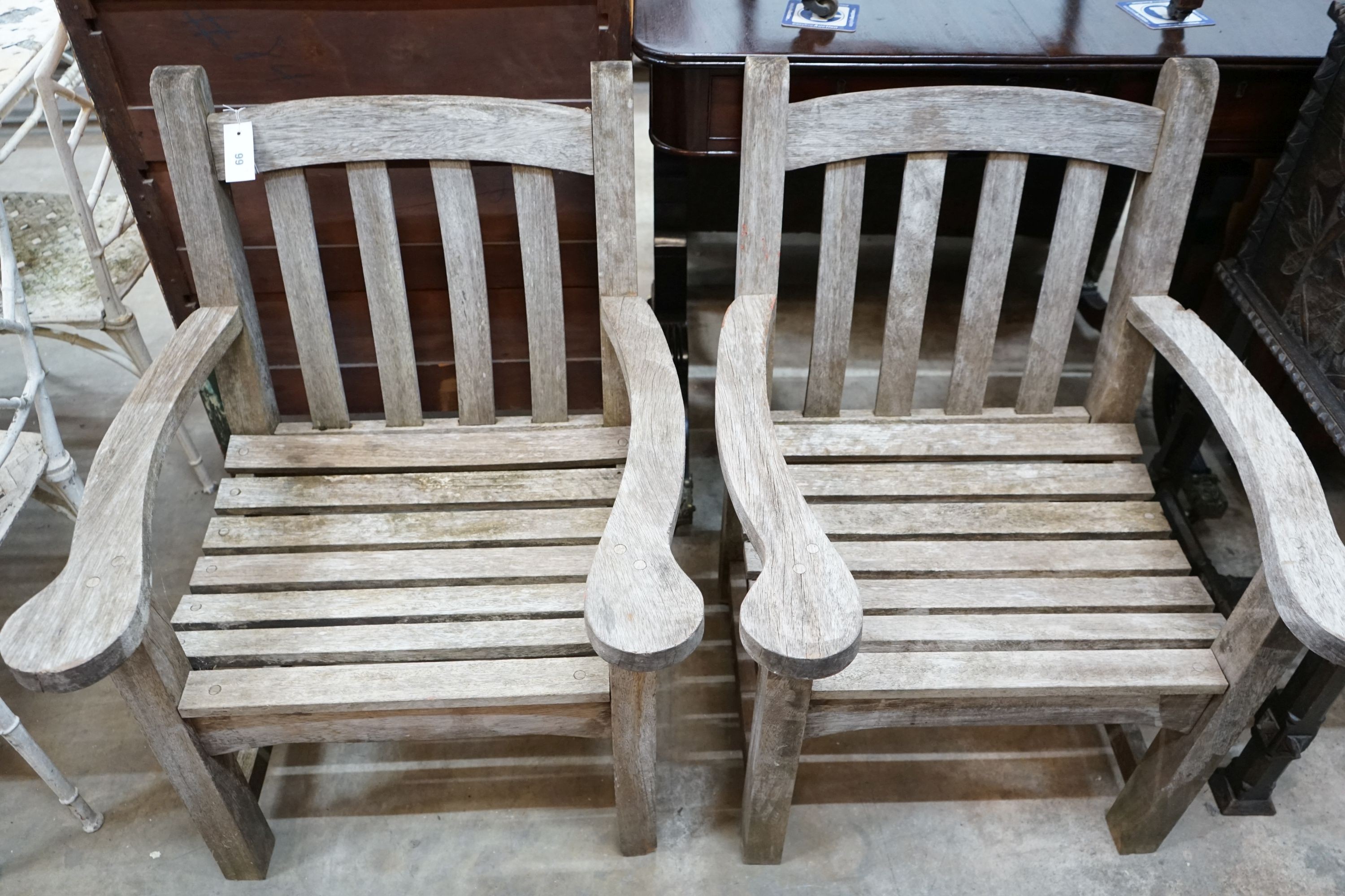 A pair of weathered teak garden armchairs, width 65cm, depth 58cm, height 87cm